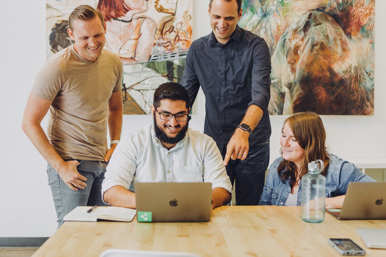 The team gathered around a laptop at a wood table